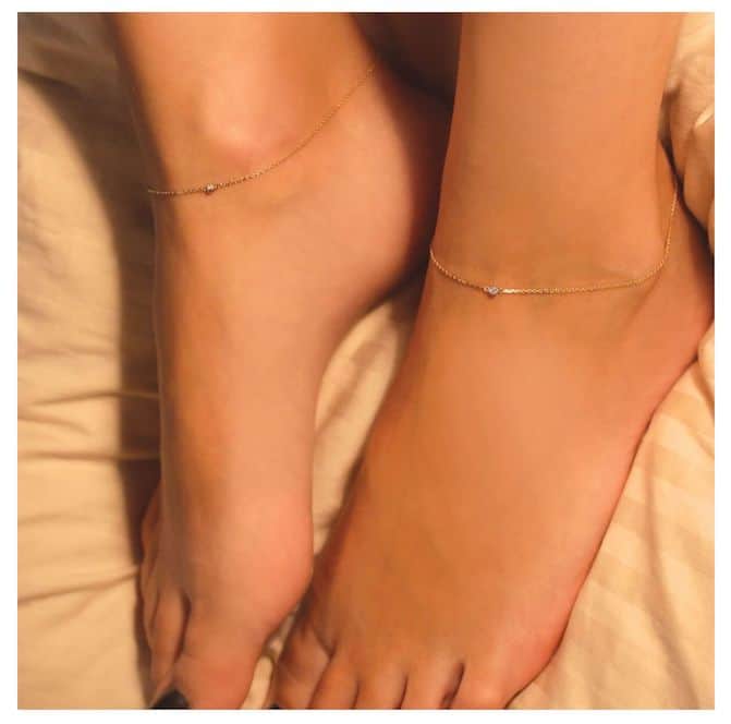 woman's feet with a slim gold anklet around each ankle