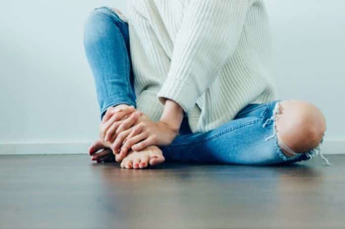 woman in jeans sitting crosslegged on her eco friendly floor