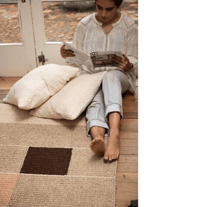 woman sitting on a Zuahaza rug and reading a book