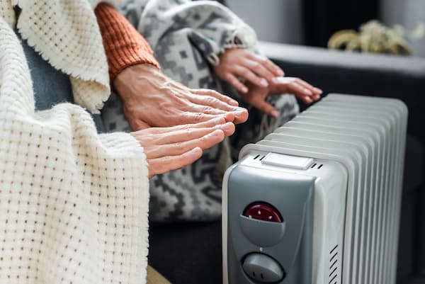 two people warming their hands with an eco-friendly electric heater in winter