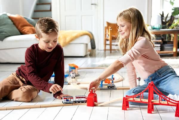 little brother and sister playing with an eco friendly train set