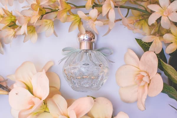 globular glass perfume bottle with mauve flowers surrounding it