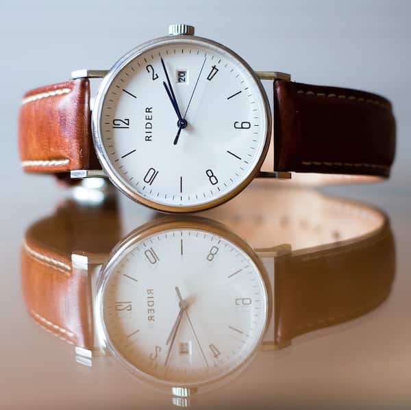 analog watch with leather strap lying sideways on a table