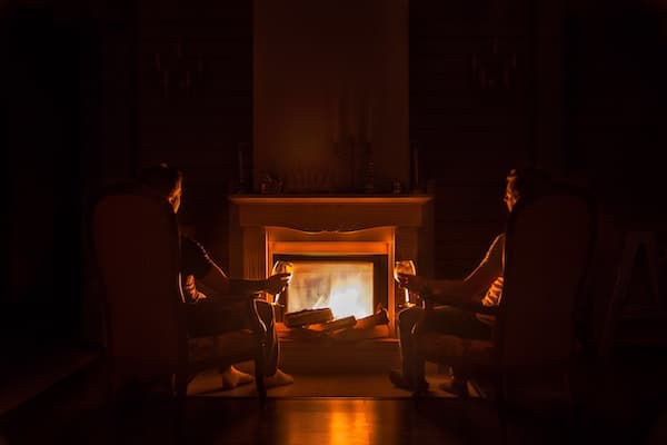 a couple sitting in front of their fireplace fire