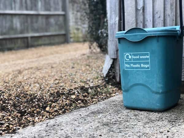 food waste bin in the foreground, in a home garden
