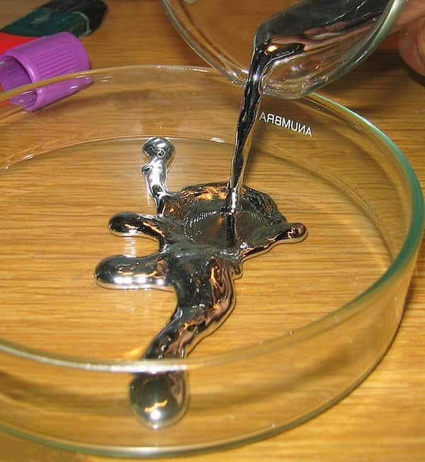 liquid mercury being poured into a glass Petri dish