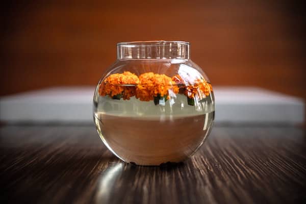 fishbowl filled with water and floating marigold flowers
