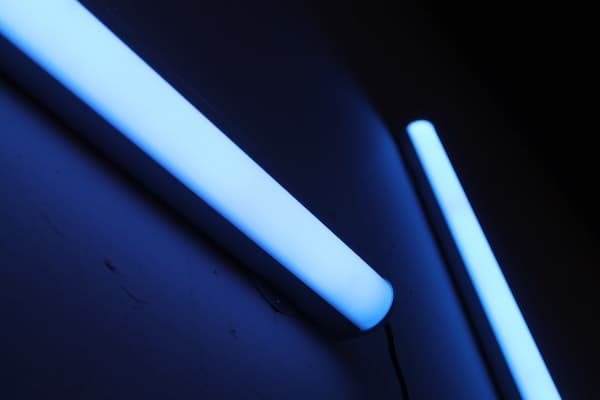 two fluorescent tubes fixed at an angle, against a dark blue background