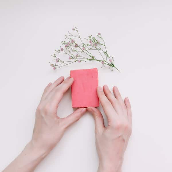 woman's hands holding a pink biodegradable soap bar