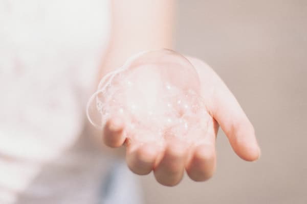 a woman's left palm holding soap bubbles