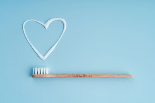 a bamboo toothbrush next to a heart-shaped smear of zero waste toothpaste