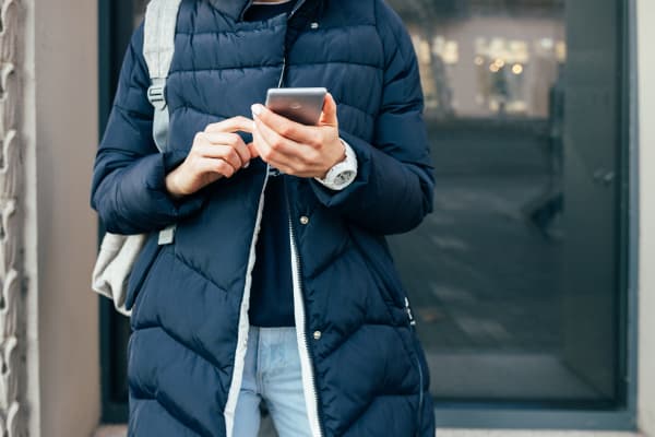 woman wearing a long puffer jacket and looking at her mobile phone